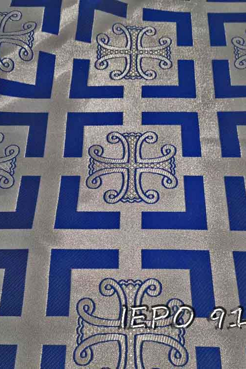 Μπροκάρ ασημένιο ύφασμα με σχέδιο μπλε σταυρούς οι οποίοι βρίσκονται εντός τετραγώνων με μπλε περίγραμμα. Το σχέδιο επαναλαμβάνεται συνεχώς.