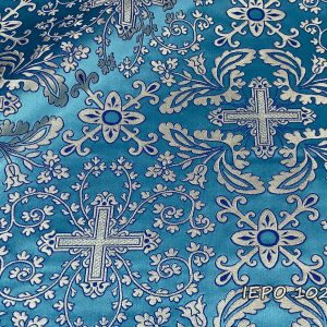 Țesătură la bază de culoare albastru deschis, cu cruci, ramuri și flori de culoare argintie cu detalii albastre.