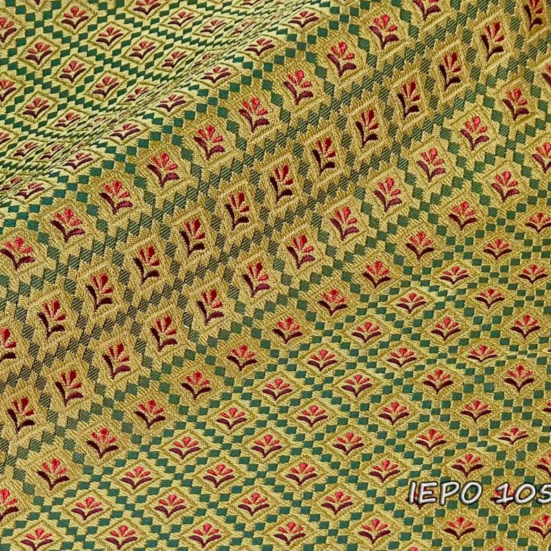 Ιερατικό ύφασμα με χρυσή βάση, σχέδιο από πράσινα μικρά τετράωνα που δημιουργούν ρόμβους, μέσα στους οποίους υπάρχουν κόκκινα και μπορντό λουλούδια.
